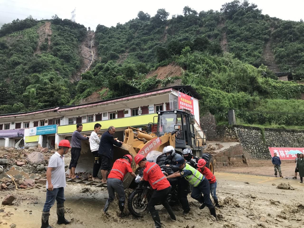 8月18日，搶險人員與民警幫助被困群眾的摩托車通過涉水路面.jpg